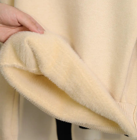 Hand touching zachte creamkleurige fleece van de Alpaca Comforttrui maxi met col.