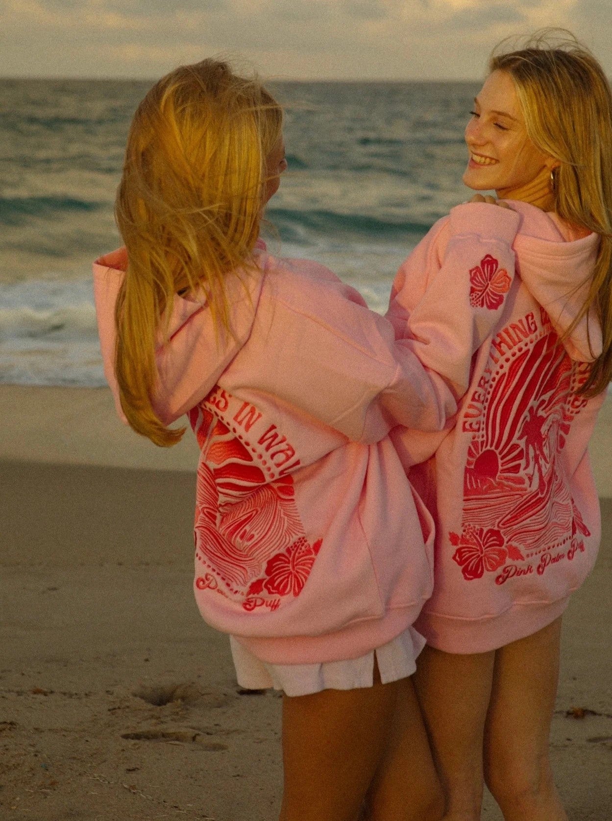 Twee mensen op het strand in Elisska Sommer-Hoodie, ultiem comfort met bloemdessin.